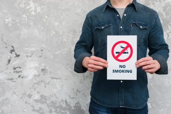 Man holding a no smoking sign for patients who want to get HD liposuction