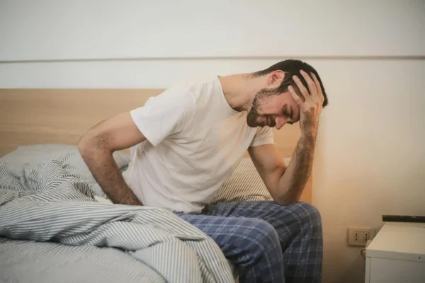 Man sitting on his bed and braving the pain after liposuction