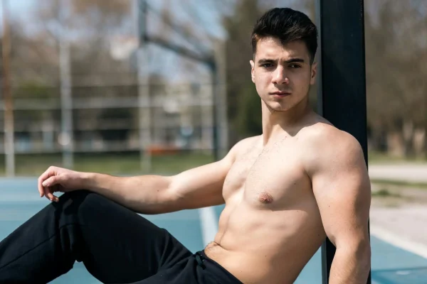 Shirtless man flexing his well built physique after getting abdominoplasty