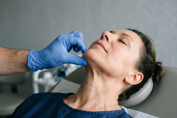 Surgeon pinch testing neck skin laxity before FaceTite vs Sofwave decision