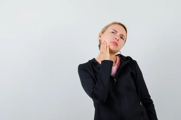Woman wearing a black jacket touching her jaw before getting fillers