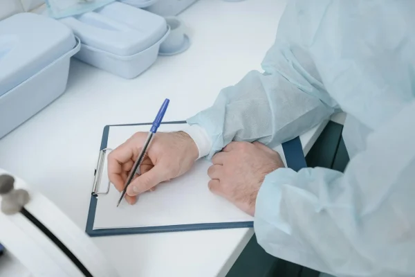 Close-up shot of a plastic surgeon writing essentials after a liposuction surgery
