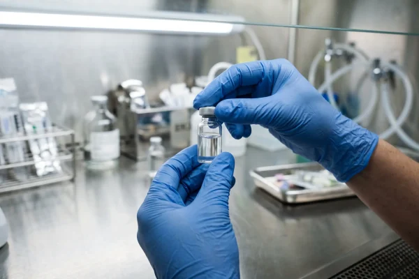 Gloved hands inspecting an unlabeled vial, showing why glutathione sourcing and sterility matter