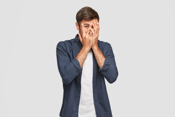 Man covering his face and standing anxiously after knowing that liposuction has risks