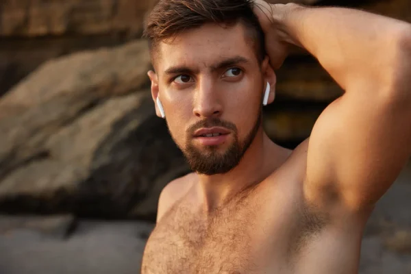 Shirtless man flexing the results of his jawline fillers