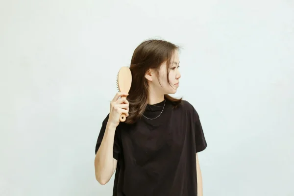 Woman brushing her hair and thinking about getting PRP injection for hair loss