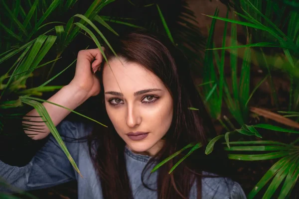 Woman with leaves as background showing off her brow lift after receiving Botox