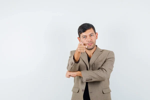 A confident young man in a blazer pointing directly at the viewer