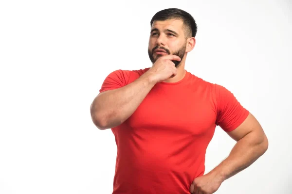 A man in a red shirt looking thoughtfully upward, representing a patient considering surgical options