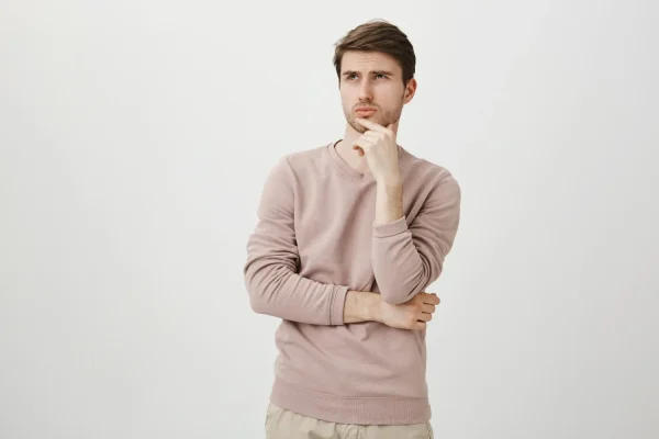 A man looking away with a skeptical, pensive expression and his hand on his chin