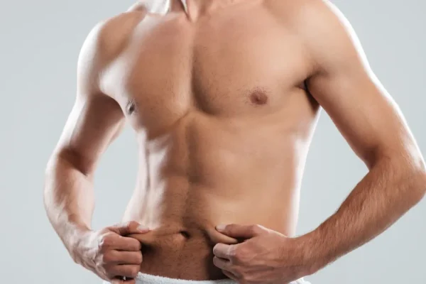 A man pinches fat on his midsection, often a key moment for those considering how liposuction can address specific body contouring