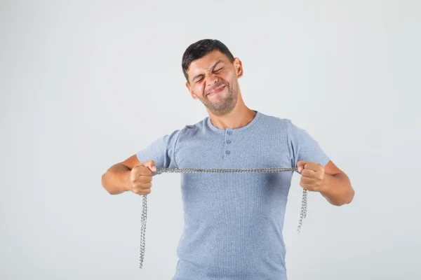 A man strains with a grimace while pulling on a metal chain