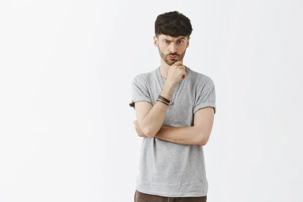 A man with a focused expression holds his hand to his chin