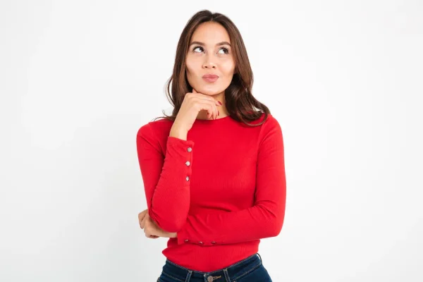 A woman in a red long-sleeve top with a contemplative expression