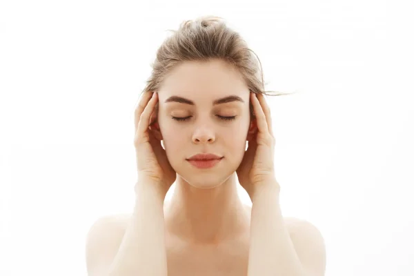 A woman with eyes closed gently holding both sides of her face, highlighting the facial areas