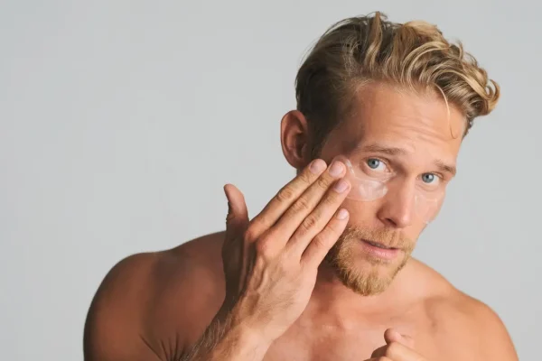 Man gently touching under-eye area checking for bumps or swelling after PDO thread lift procedure