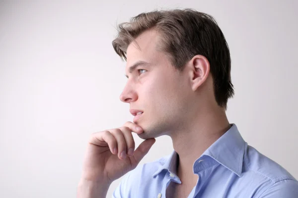 Man in blue shirt touching chin while considering the pros and cons of Botox treatment for double chin