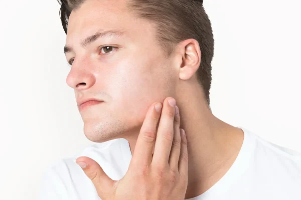 Man touching his jawline to examine facial contour before jawline filler treatment