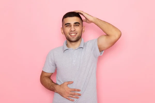 Smiling man with hand on stomach showing satisfaction with firm abdomen after tummy tuck recovery