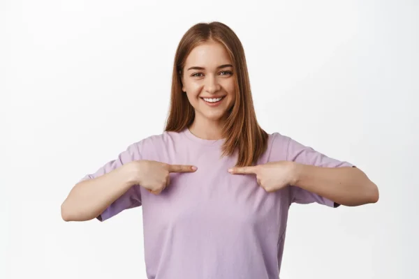 Smiling woman pointing to herself as a candidate for tummy tuck surgery