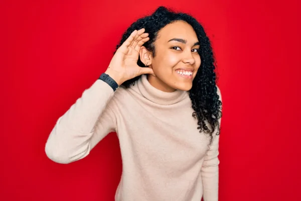 Smiling woman with hand near ear listening to understand the FaceTite procedure