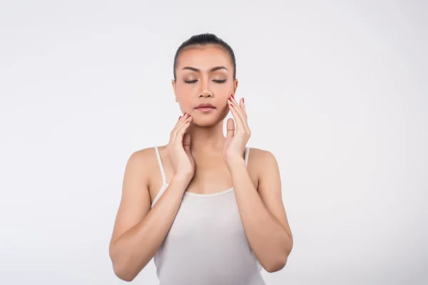 Woman gently touching her face with eyes closed, demonstrating areas to avoid rubbing after Botox treatment.