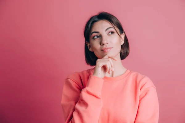 Woman thoughtfully touching her chin while considering how long dermal fillers last