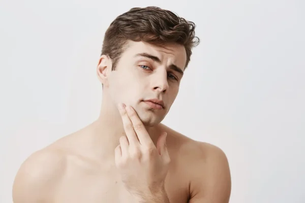 Young man evaluating his facial skin and jawline as a candidate for FaceTite treatment