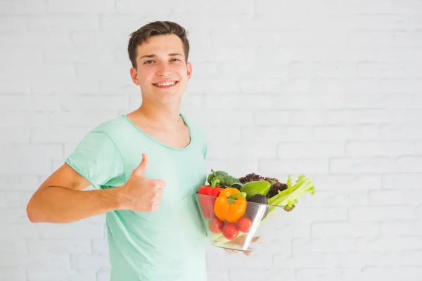 Young man giving thumbs up while holding a bowl of nutrient-rich vegetables for post-surgery recovery
