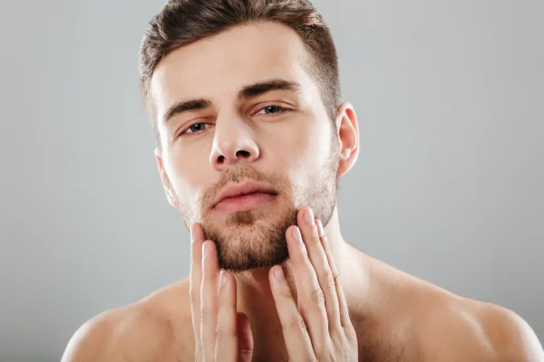 Young man touching his jawline and facial skin evaluating results after PDO thread lift treatment