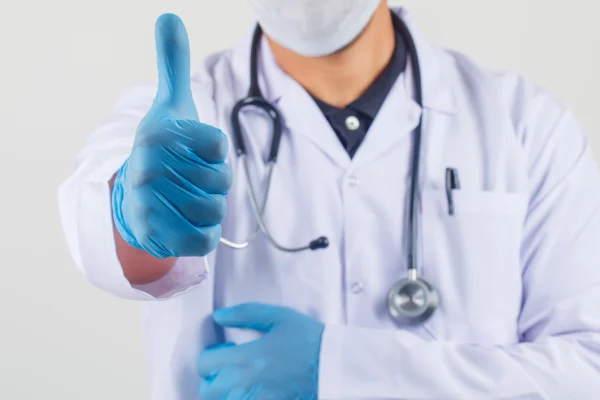 male doctor in white coat and mask making thumb up