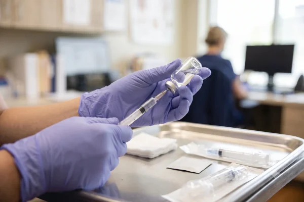 Physician assistant preparing an NAD+ injection with gloved hands