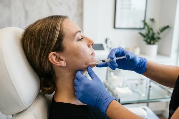 Provider injecting jawline filler during a touch-up appointment
