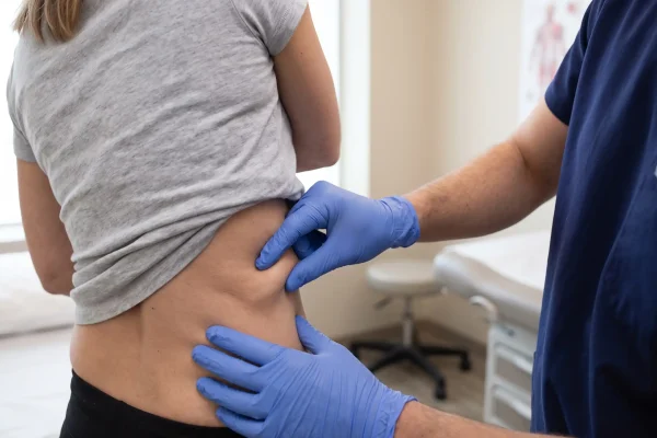 Skin pinch test checking liposuction candidacy at a Tampa consultation