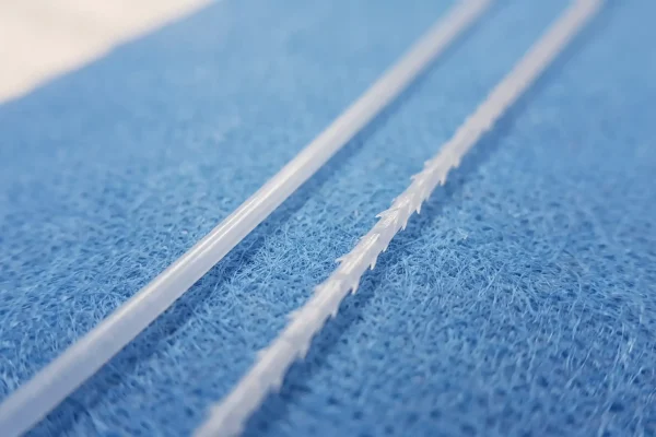 Smooth and barbed PDO threads side by side showing the barbs that grip tissue