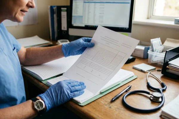 Surgeon reviewing medical clearance forms for cosmetic surgery patient