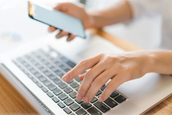 woman hand with mobile phone over laptop