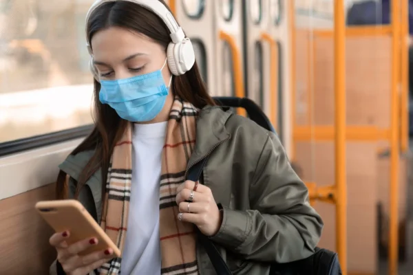 Woman with medical mask using tablet while traveling