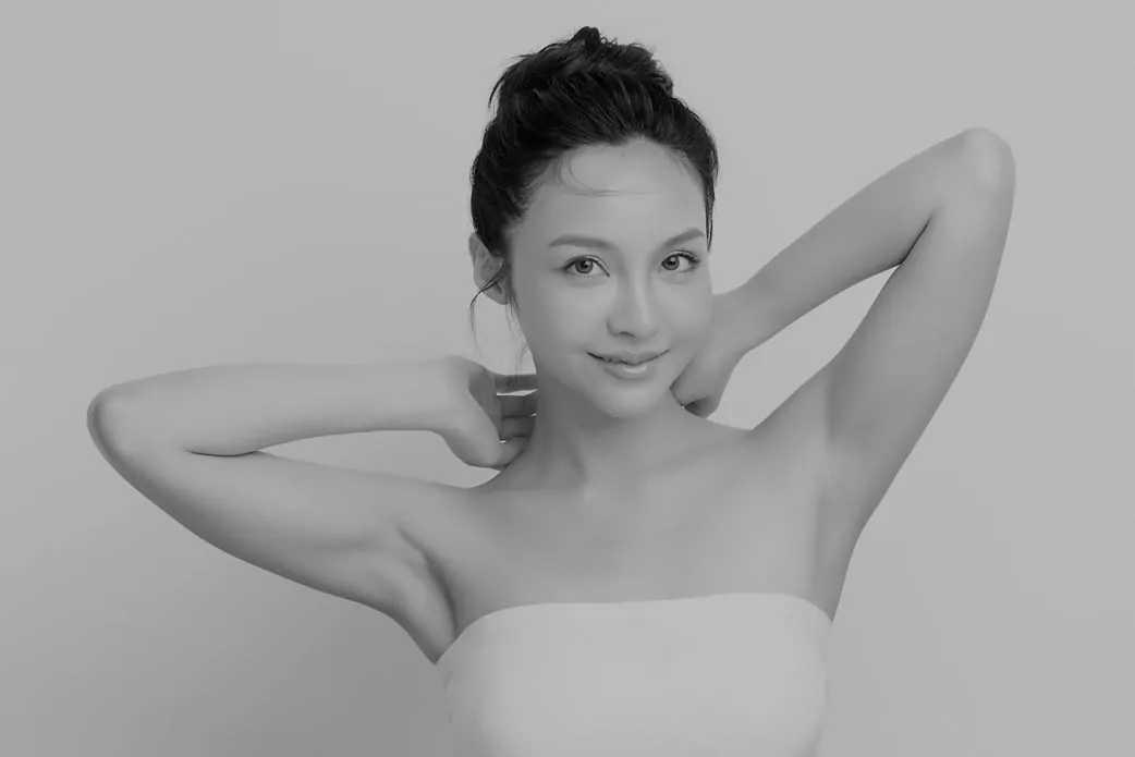 female model with hands behind neck after liposuction showing toned arms