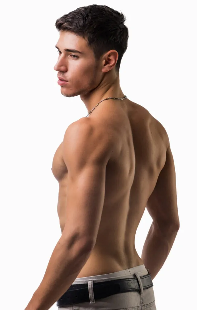 Shirtless man facing sideways in studio lighting after plastic surgery