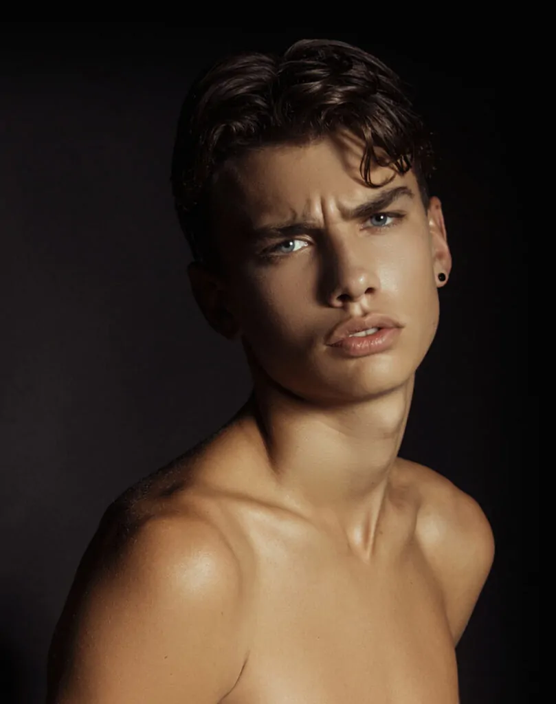 Shirtless man on dark background.