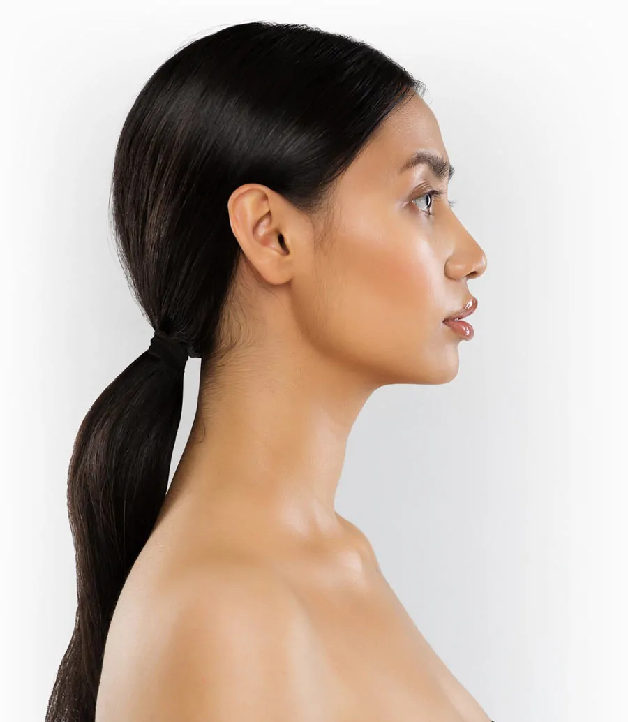 Profile of woman with ponytail and clear skin after plastic surgery