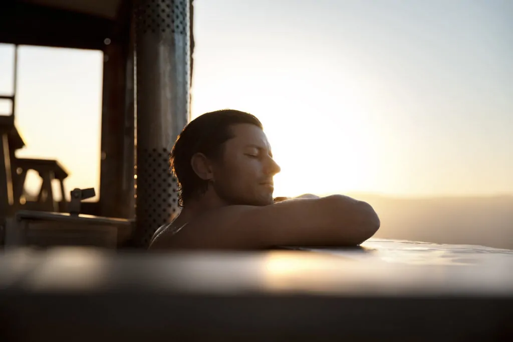 Man relaxing in hot tub at sunset
