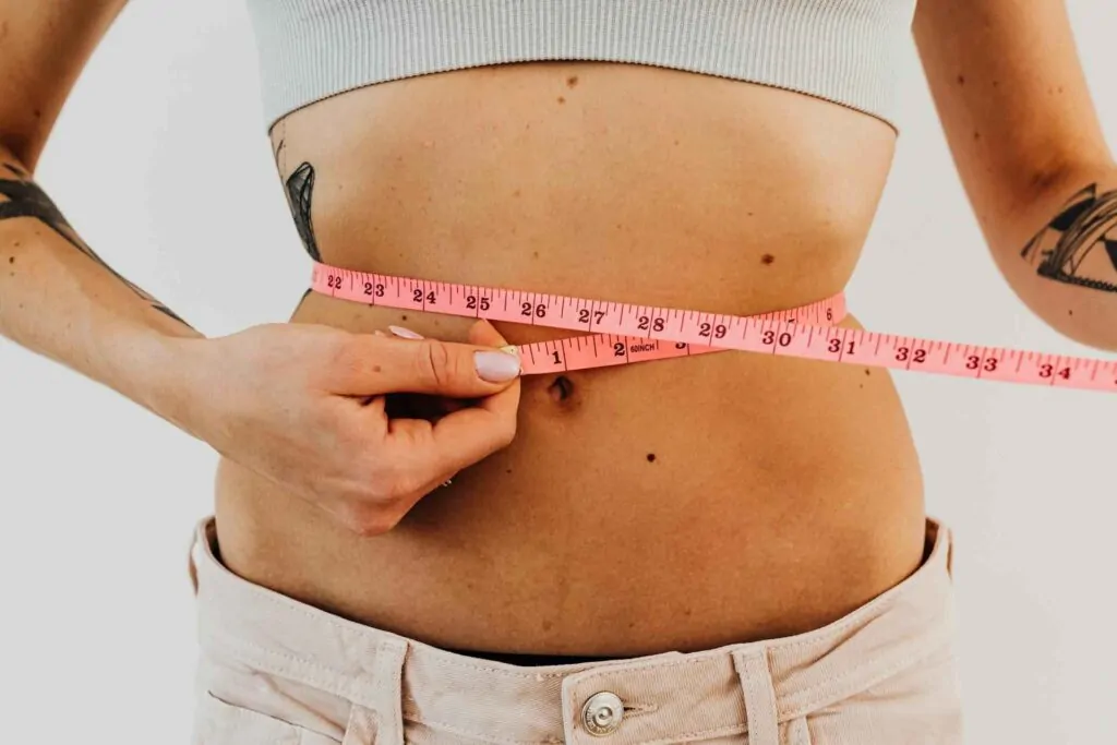 A woman using measuring tape to measure waist