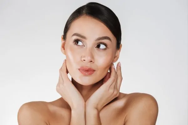 woman holding hands close to her healthy face after recovery from plastic surgery