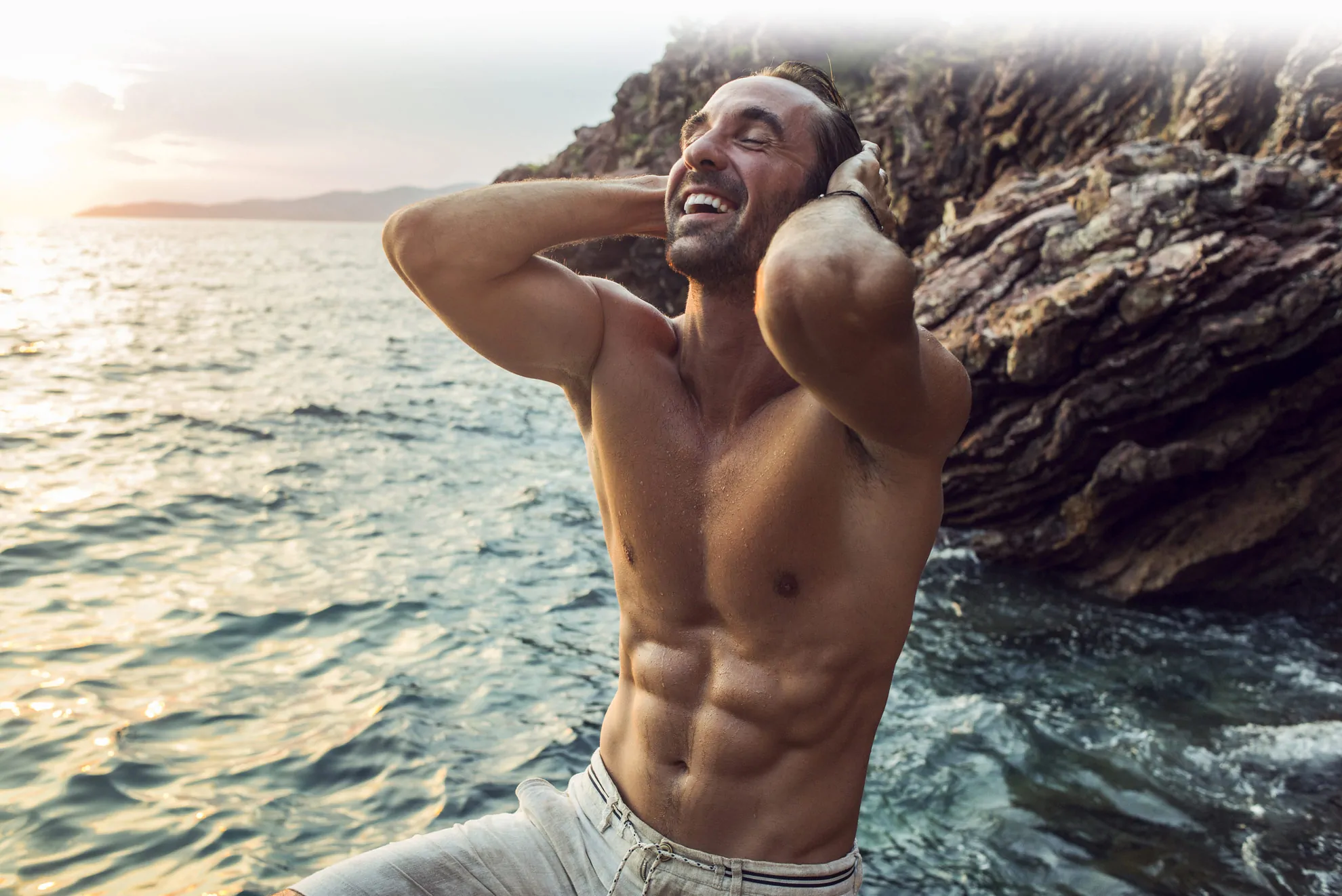 Man flexing his plastic surgery results by the beach