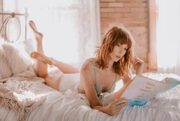 A woman on a bed reading about tummy tuck procedures