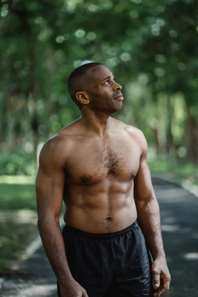 a man wandering in the forest with sculpted abs