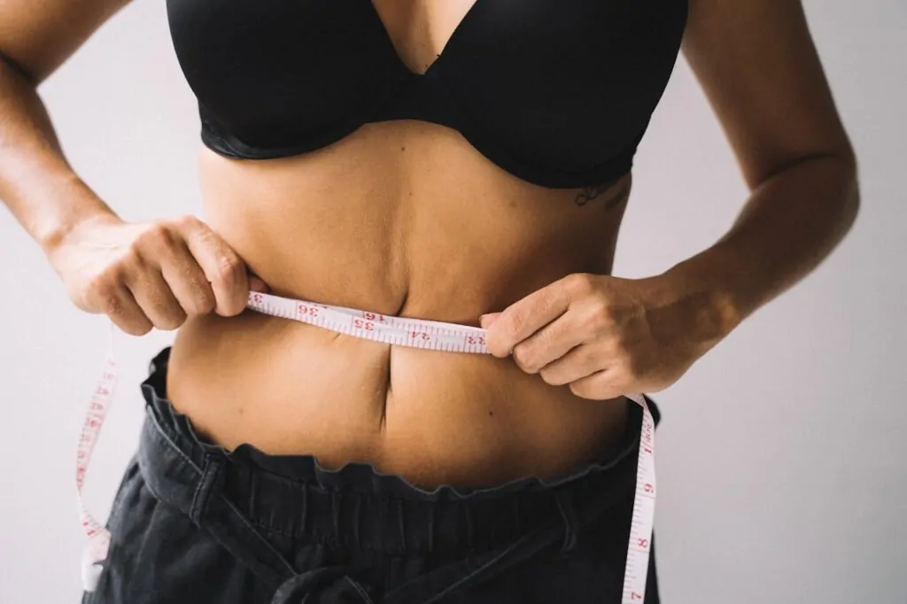 a woman measuring her belly before liposuction