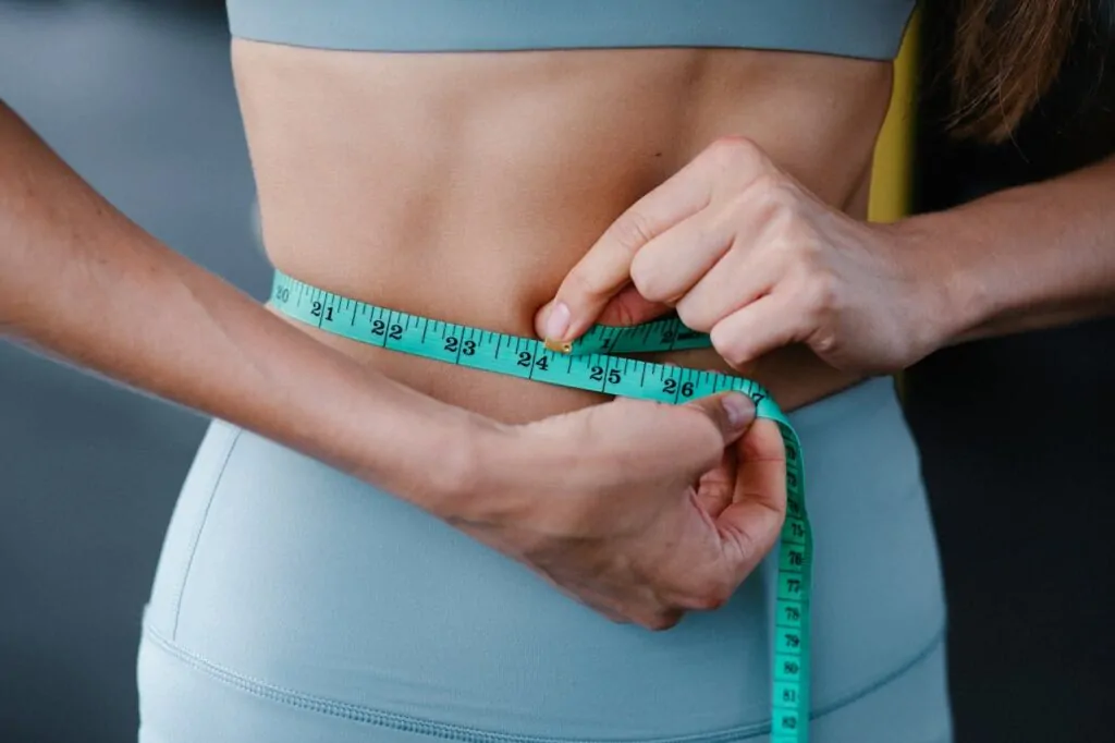 a woman measuring her belly before a liposuction procedure